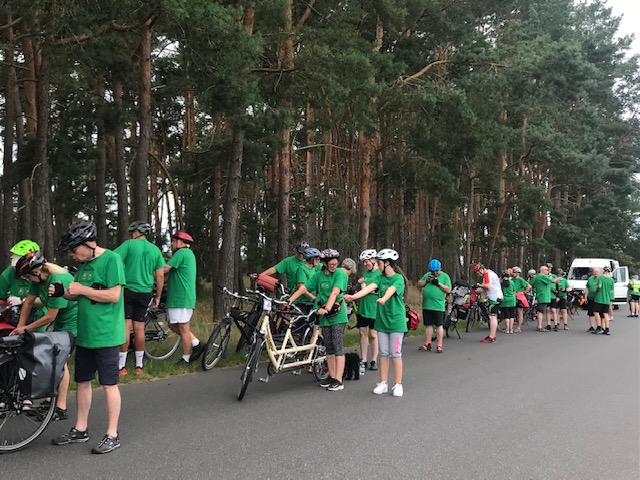 Die Teilnehmer des Tandem-Camps machen eine Pause am Straßenrand, im Hintergrund ein Begleitauto.